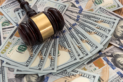 photo of a gavel laying on top of stacks of hundred dollar bills