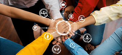 employees with their hands overlapping one another to illustrate collaborative teamwork in the workplace