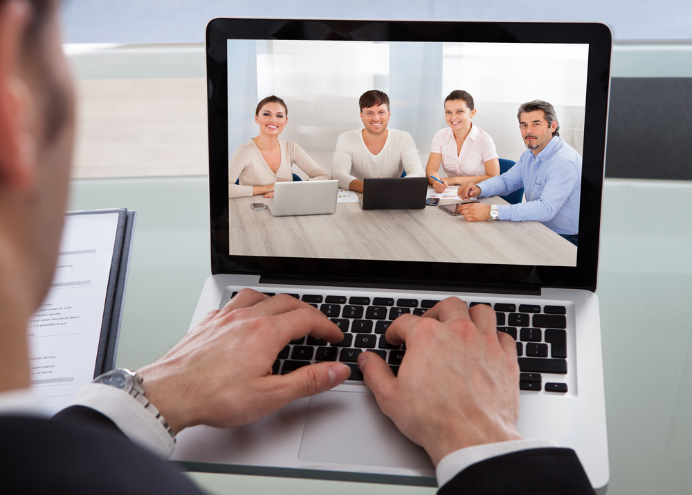 photo of business person engaged in a video chat with coworkers in another location