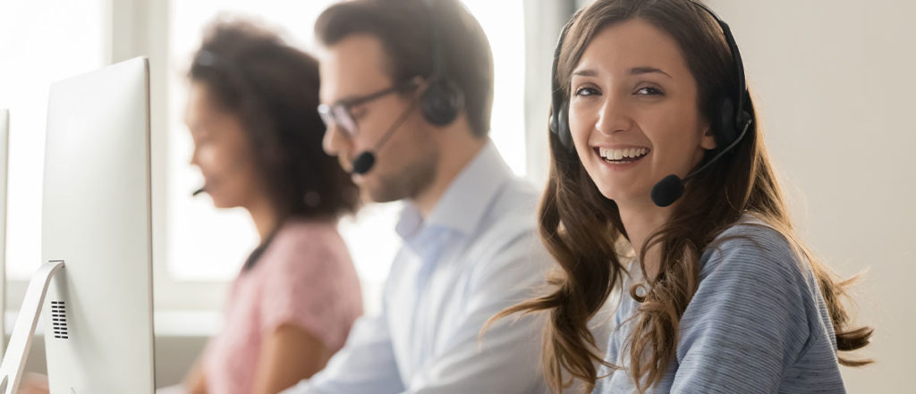 photo of smiling female hr call center representative using headphone at computer 