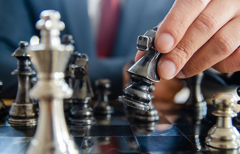 photo of a businessman strategically moving chess pieces on a chessboard