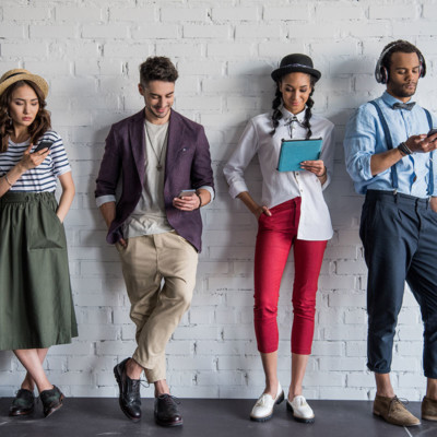 A group of four young and diverse millennials looking at their mobile devices. 