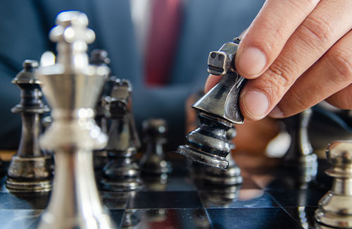 small - photo of a businessman strategically moving chess pieces on a chessboard
