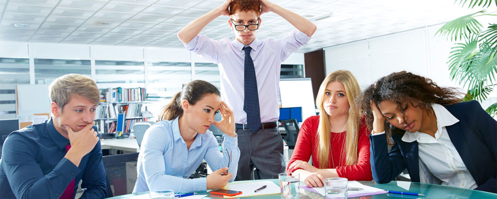 young businesspeople sitting at table completely stressed out and mad with each other