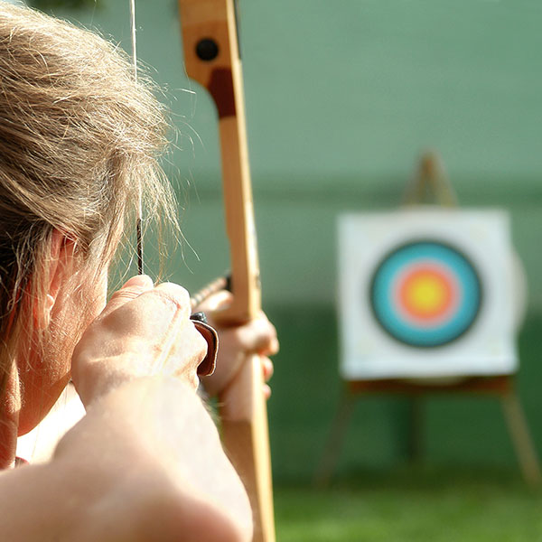 Picture of a woman aiming a bow and arrow at a target